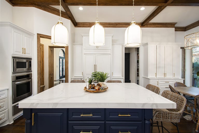 Three pendant lights hanging above kitchen island with stone countertop from coffered ceiling in Dallas home remodel